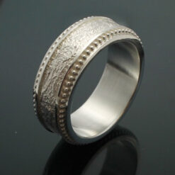 The Cuban Wedding band with milgrain edges next to a tobacco leaf texture