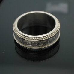 The Cuban Wedding band with milgrain edges next to a tobacco leaf texture