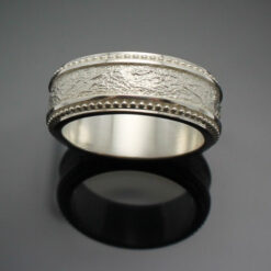 The Cuban Wedding band with milgrain edges next to a tobacco leaf texture