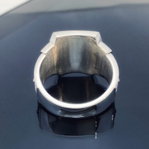 A silver ring sitting on top of a black surface.